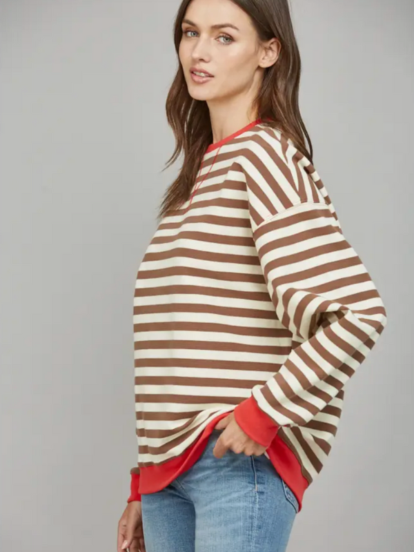 Woman wearing a brown and white striped sweater with red accents on a gray background