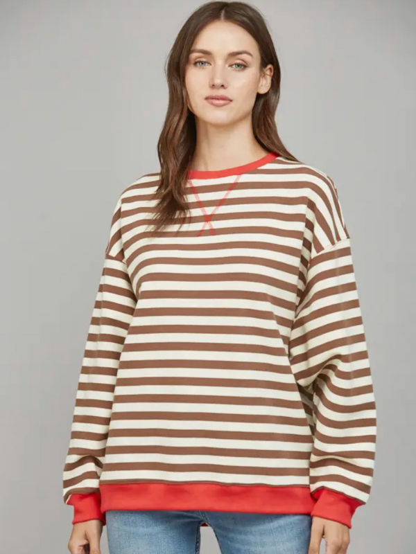 Woman wearing a brown and beige striped sweater with red trim on a gray background