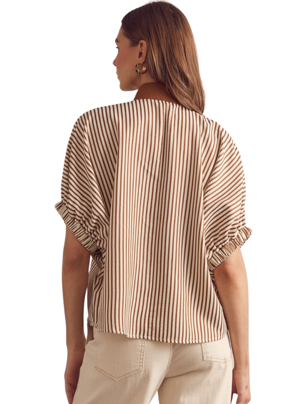 Woman wearing a striped shirt and beige pants on a white background