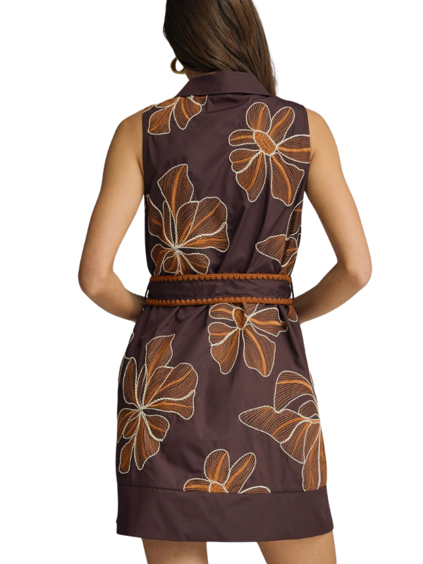 A woman shown from the back wearing a sleeveless collared dress with a brown base and large tan floral pattern, against a plain white background.