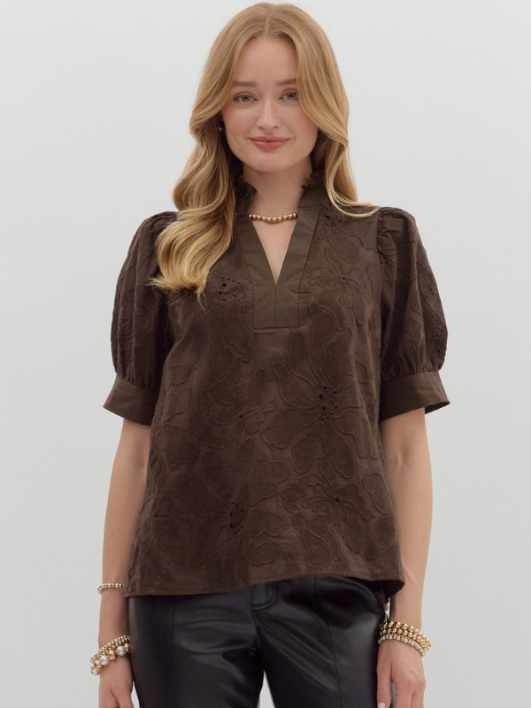 Woman wearing a brown textured blouse with puff sleeves against a white background