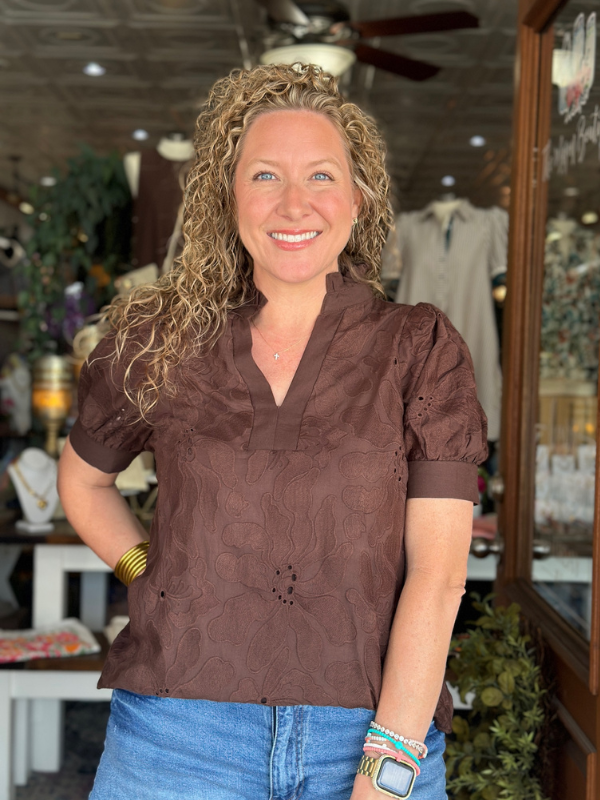 Woman wearing a brown blouse with lace details in a store setting