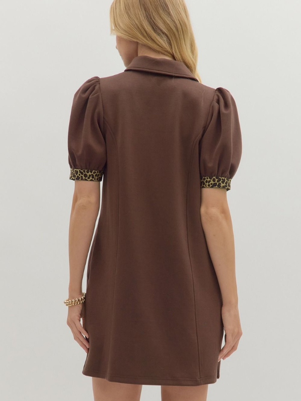 Brown dress with leopard print trim on sleeves and hem, worn by a person on a light gray background