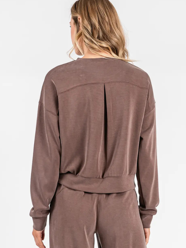 Brown long-sleeve top worn by a person on a white background