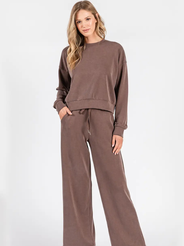 Woman wearing a brown sweatshirt and pants set on a white background