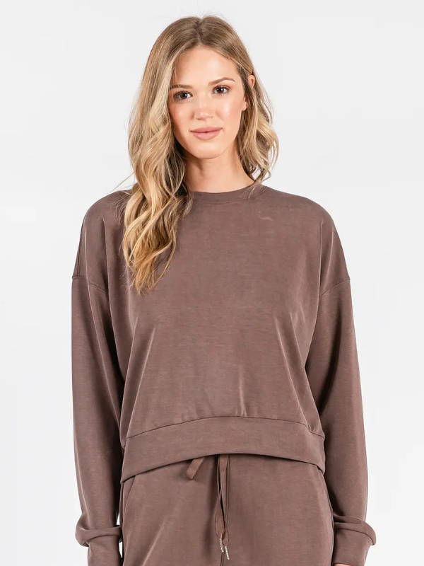 Woman wearing a brown sweatshirt and pants on a white background