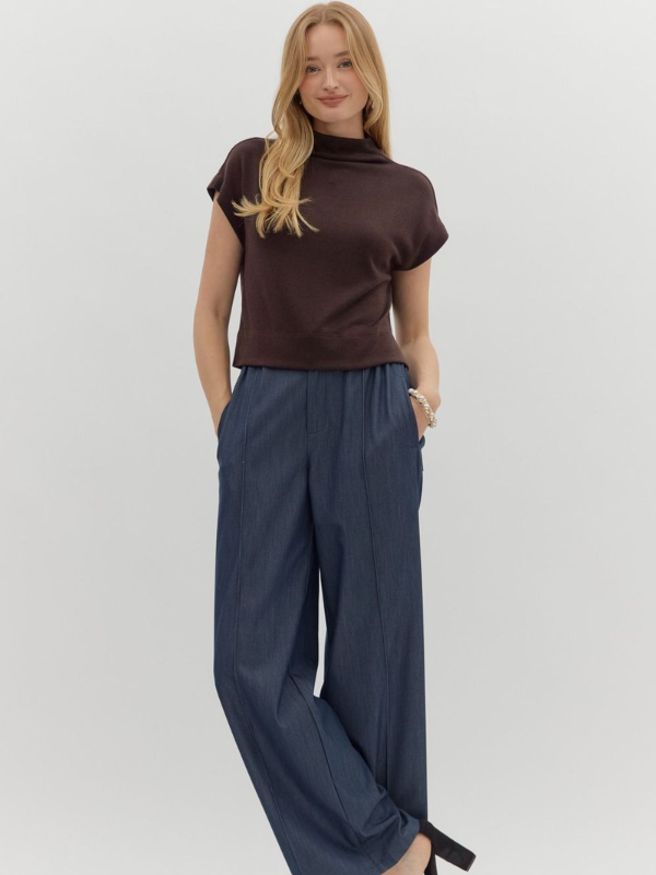 Woman wearing a brown top and navy pants on a white background