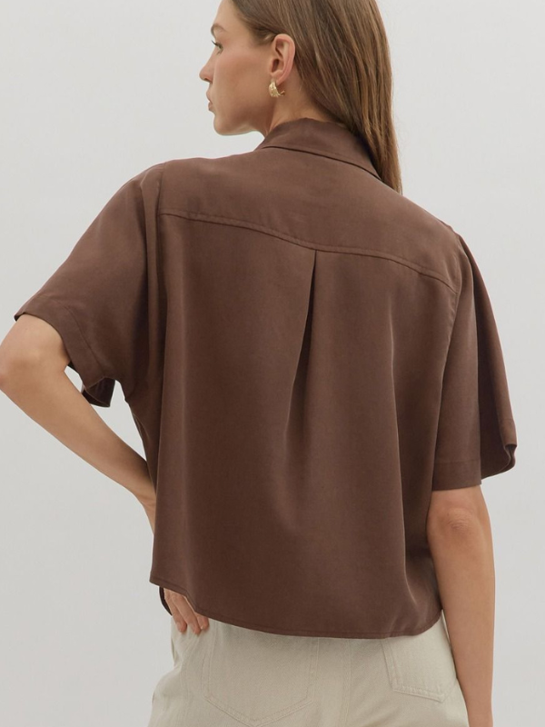 Woman wearing a brown shirt against a plain background