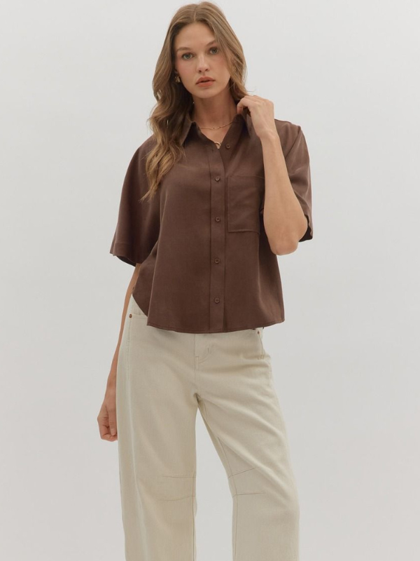 Woman wearing a brown shirt and beige pants on a white background