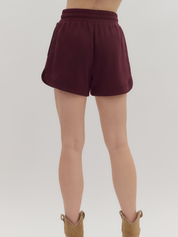 Maroon shorts worn by a person on a white background