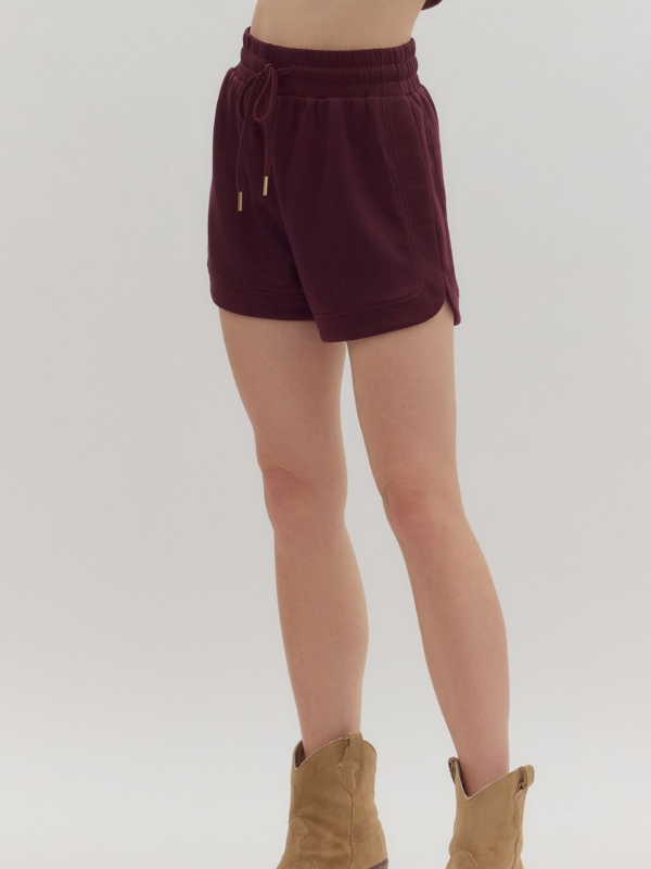 Maroon shorts worn by a person on a white background