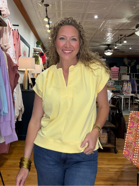 Woman wearing a yellow blouse and blue jeans in a store setting