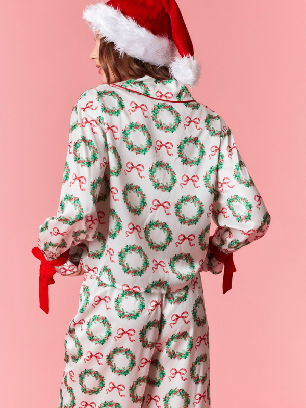 Person wearing a festive onesie with Christmas patterns on a pink background