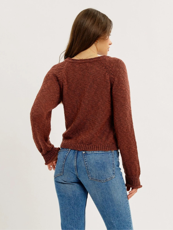 Person wearing a brown sweater and blue jeans on a white background