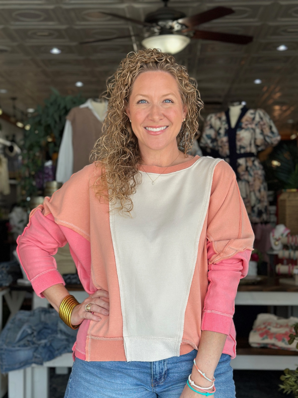 Woman wearing a pink and white top with a blurred store interior background