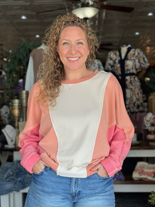 Woman wearing a pink and white top with a blurred store background