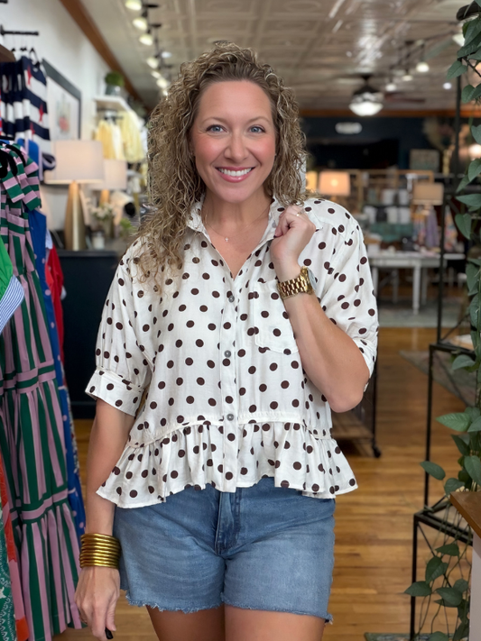 woman wearing a brown and cream polka dot top in a store
