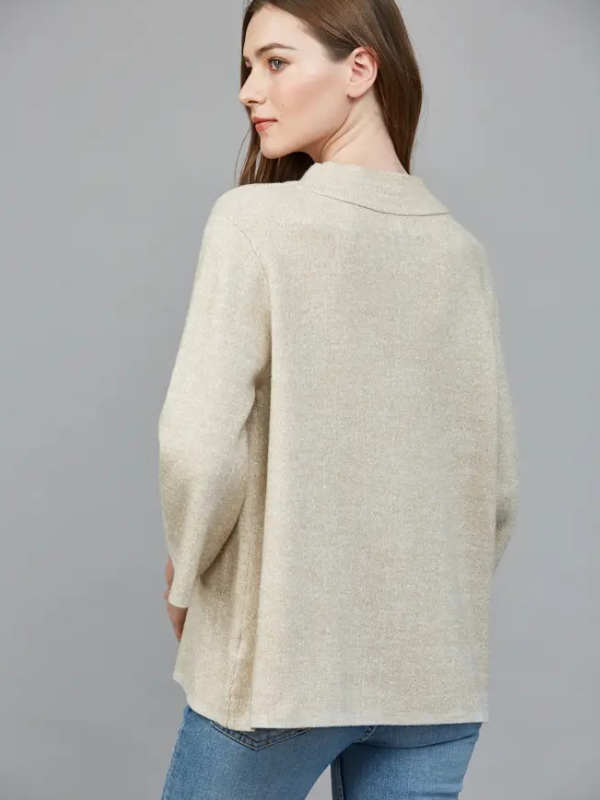 Woman wearing a beige cardigan over a blue top on a gray background