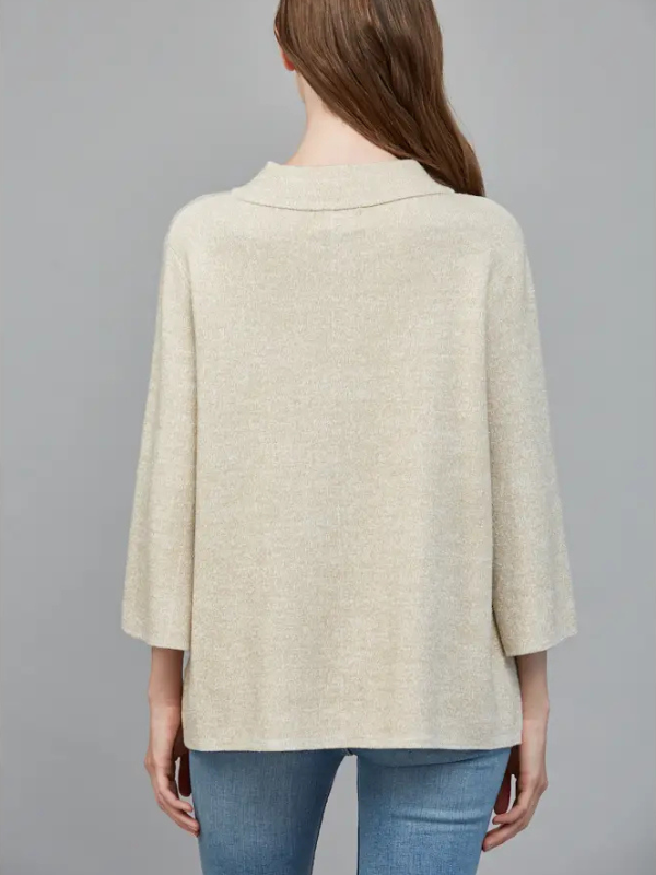 Person wearing a beige poncho over a blue top on a gray background