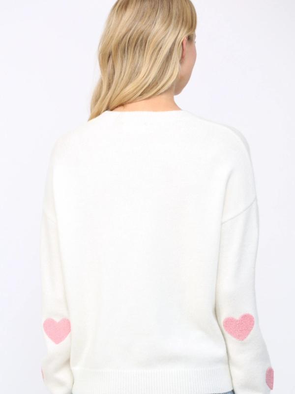 White sweater with pink heart designs on a white background
