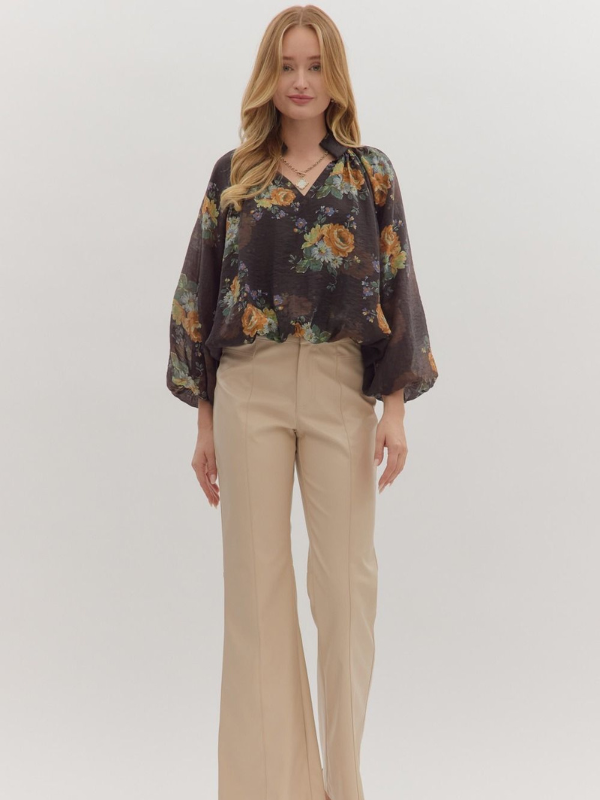 Woman wearing a floral blouse and beige pants on a white background