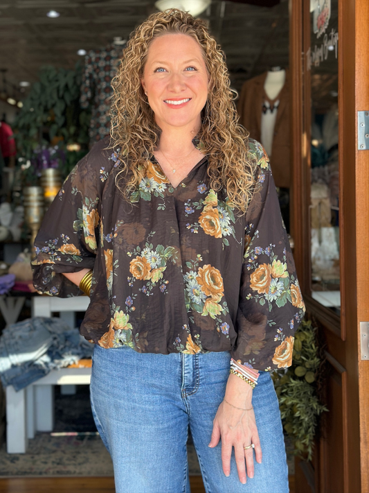 Woman wearing a floral blouse and jeans in a store setting
