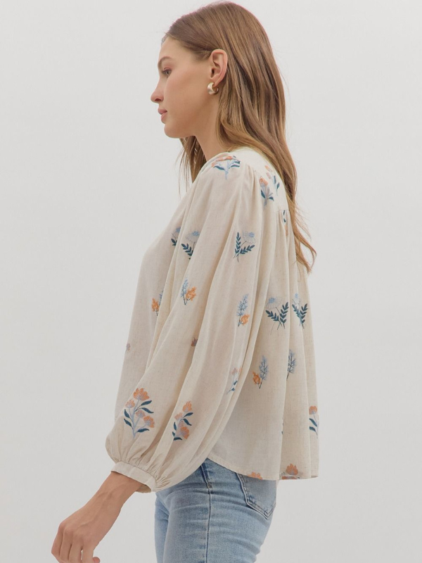 Woman wearing a beige blouse with floral embroidery on a white background