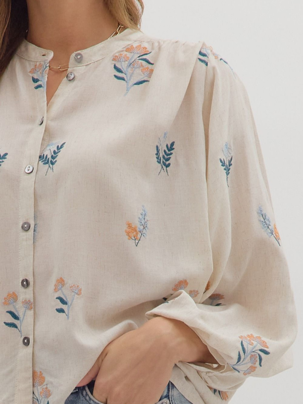 Close-up of a white blouse with floral embroidery on a plain background