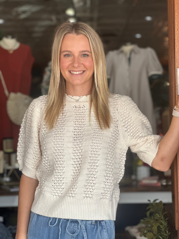 Woman wearing a textured white sweater in a clothing store