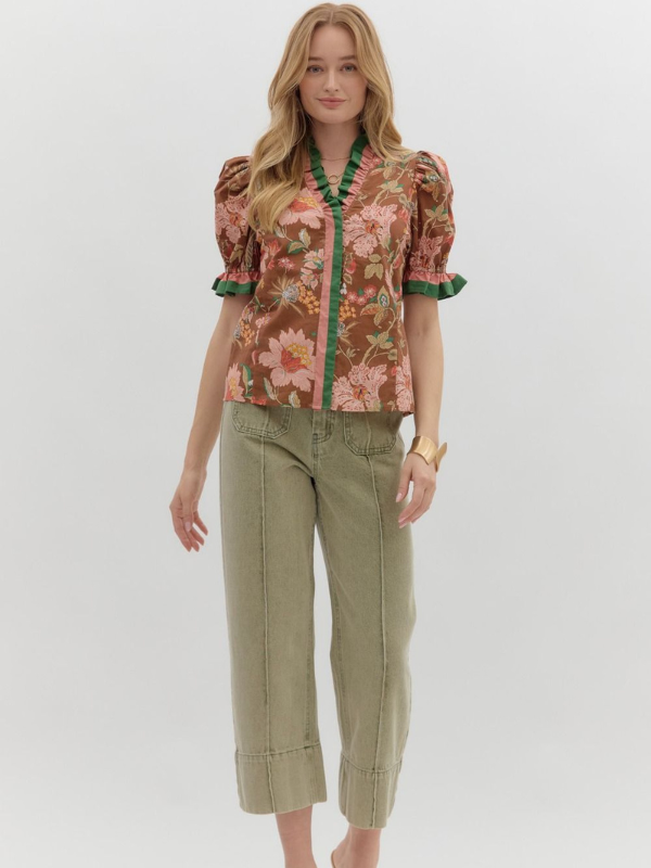 Woman wearing a floral blouse and green pants on a white background