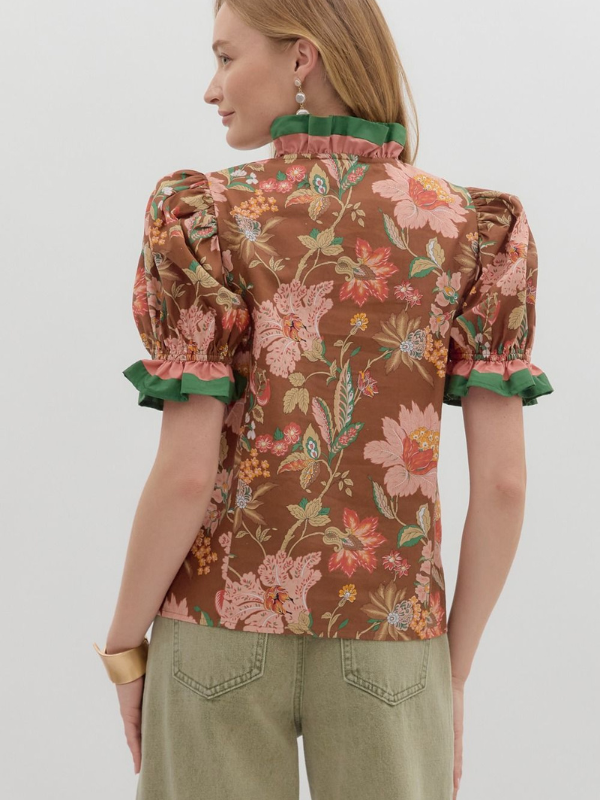 Woman wearing a floral blouse with puffed sleeves on a plain background