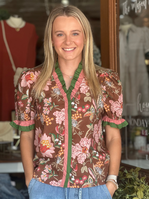 Woman wearing a floral blouse with a blurred store interior background