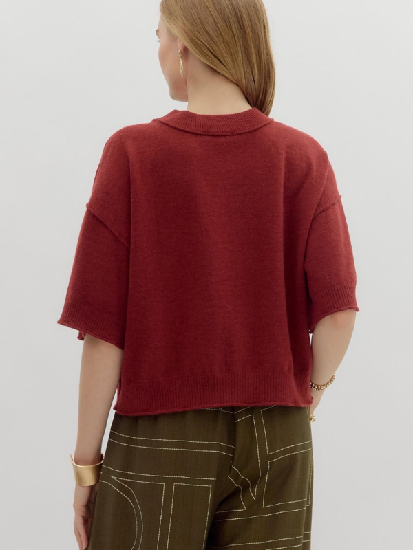 Person wearing a red sweater and green pants on a plain background