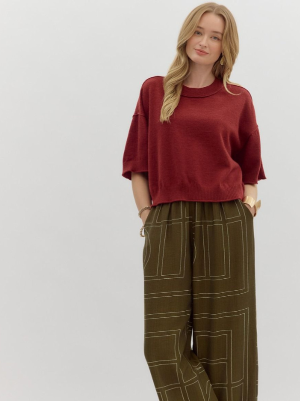 Woman wearing a red sweater and green pants on a white background