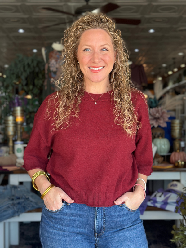 Woman wearing a red sweater and blue jeans in an indoor setting