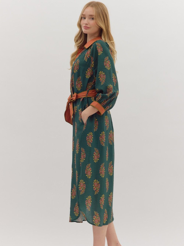 Woman wearing a green patterned dress with a belt on a white background