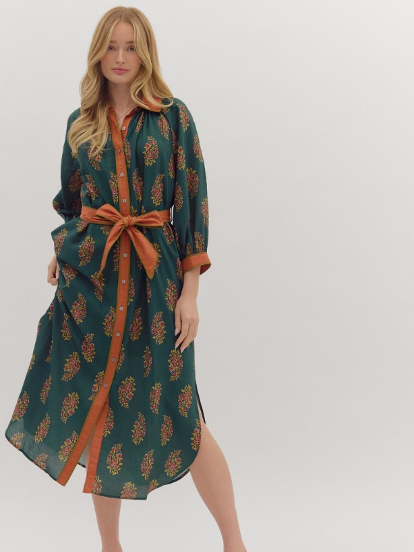 Woman wearing a green and orange patterned dress with a belt on a white background
