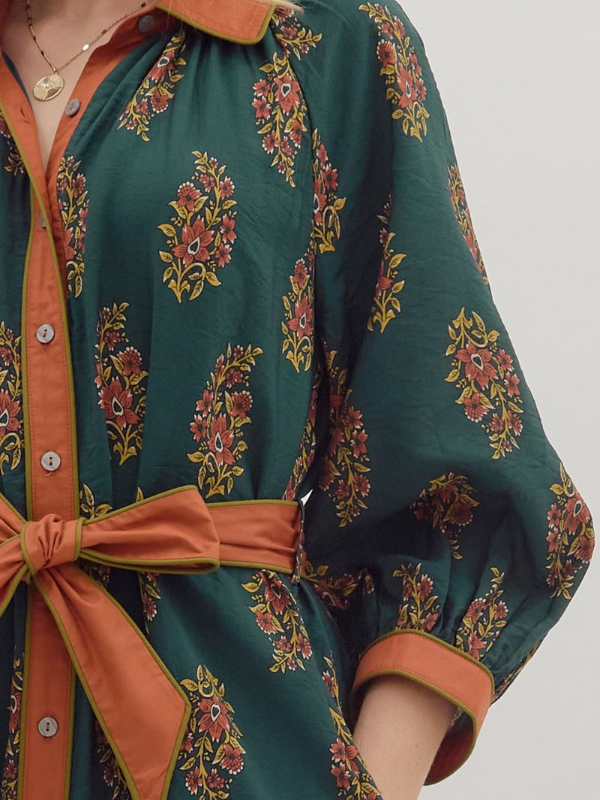 Green dress with floral pattern and orange accents on a plain background