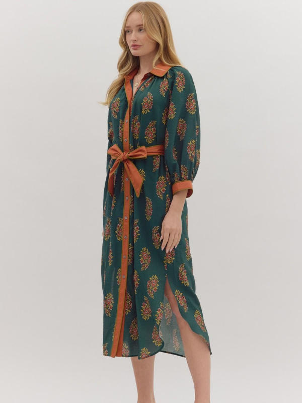 Woman wearing a green dress with orange pattern and belt on a white background