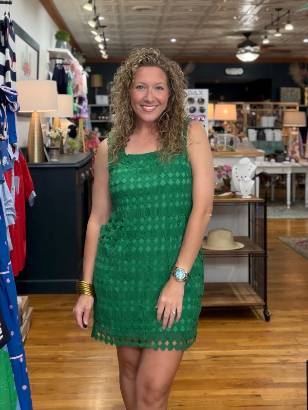 Woman in a green dress standing in a store with various items in the background