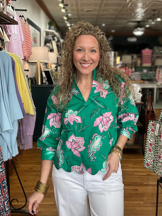 Woman wearing a green floral blouse in a clothing store