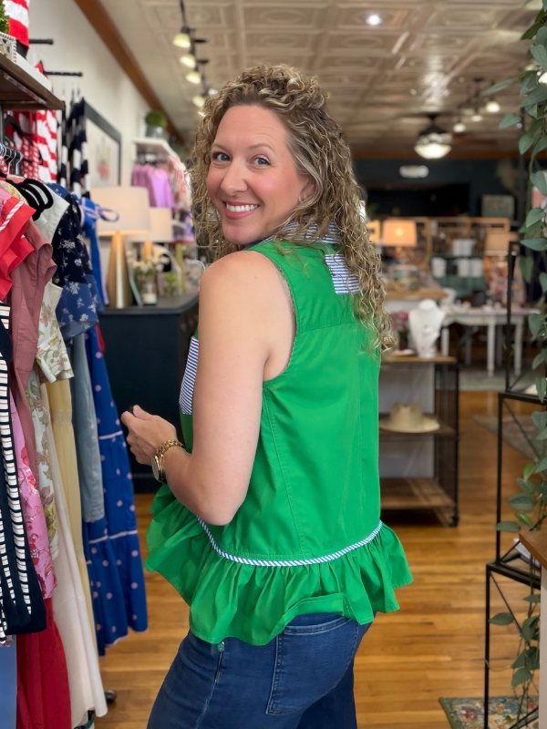 Woman wearing a green top with ruffled details in a store setting