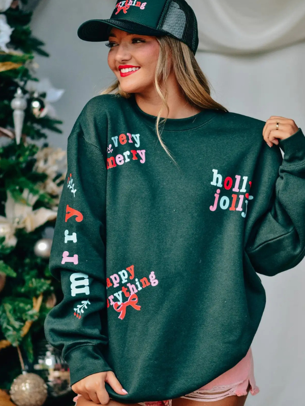 Woman wearing a green sweater with festive text in front of a Christmas tree.