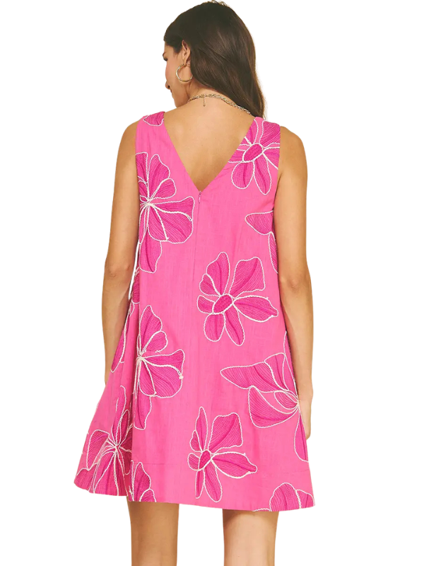 Woman wearing a pink dress with floral patterns on a white background