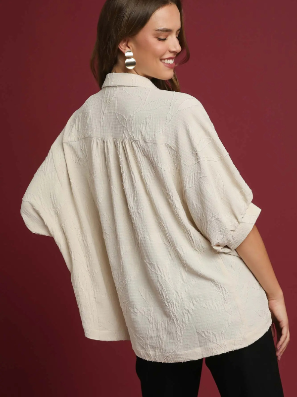 Woman wearing a beige textured blouse against a red background