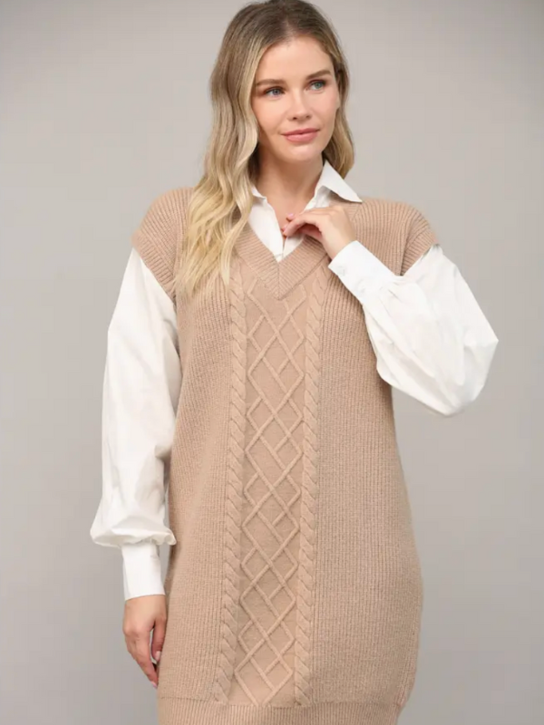 Woman wearing a beige knitted vest over a white shirt on a gray background