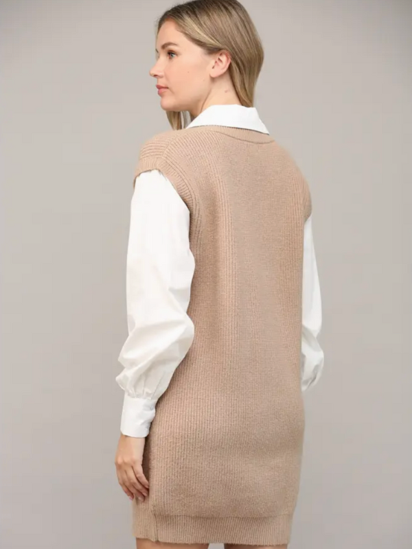 Woman wearing a beige knitted vest over a white shirt on a plain background