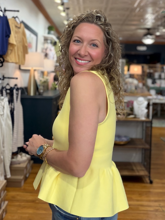 Woman wearing a yellow sleeveless top in a store setting