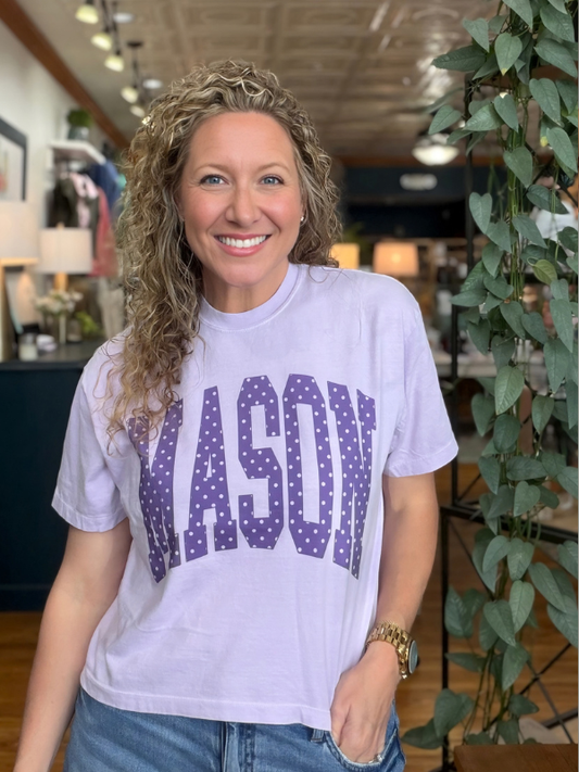 woman wearing an orchid boxy top with polka dot words saying Mason