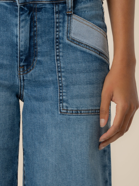 Close-up of blue jeans with a hand touching the pocket on a beige background
